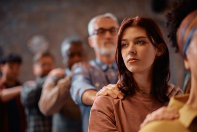 young pensive woman participating in group therapy at mental health center.